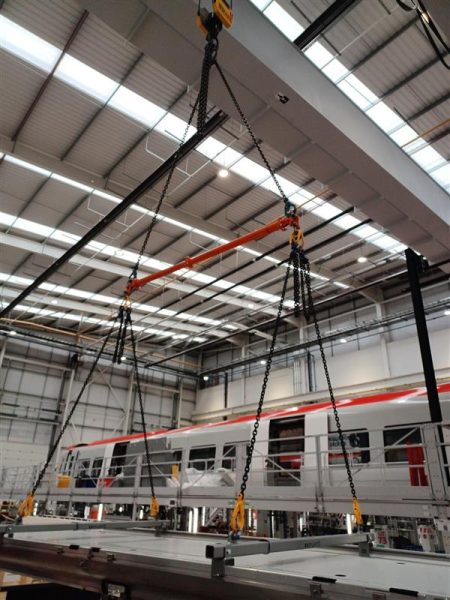 A train is being lifted using Britlift equipment in a large warehouse.