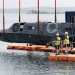 Britlift supports leading edge maritime defence company 1 A black submersible is being lowered into the water from a quay using red Britlift straps, whilst workers in safety gear supervise this maritime defence operation.