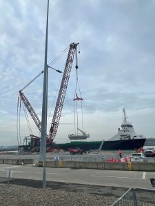 A crane using Britlift bespoke beams lifts cargo from a dock to a ship, whilst workers oversee the operation at a port under a cloudy sky. A crane using Britlift bespoke beams lifts cargo from a dock to a ship, whilst workers oversee the operation at a port under a cloudy sky.